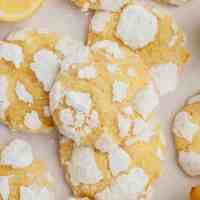 Several lemon crinkle cookies on a piece of parchment paper.