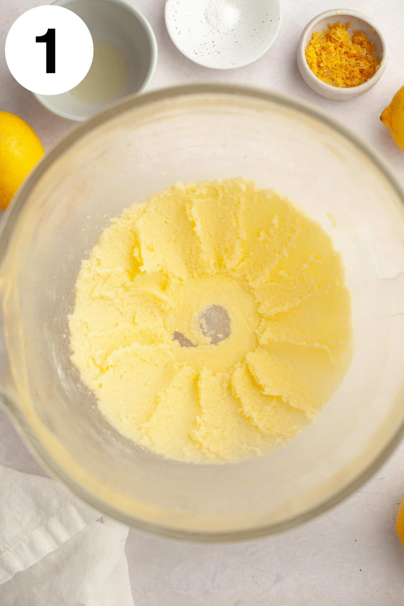 An overhead view of creamed butter and sugar in a glass mixing bowl. 