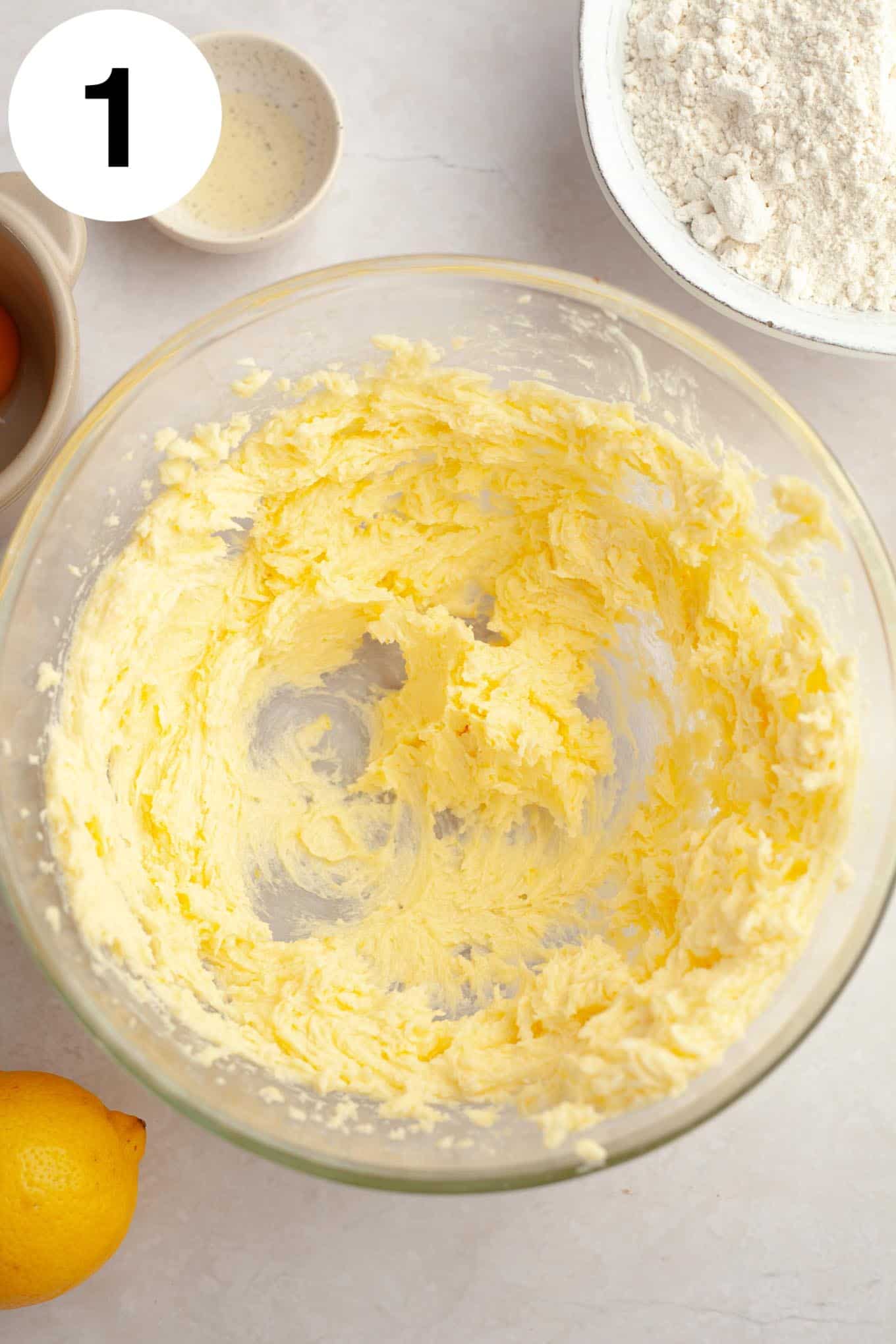 An overhead view of creamed butter in a glass mixing bowl. 