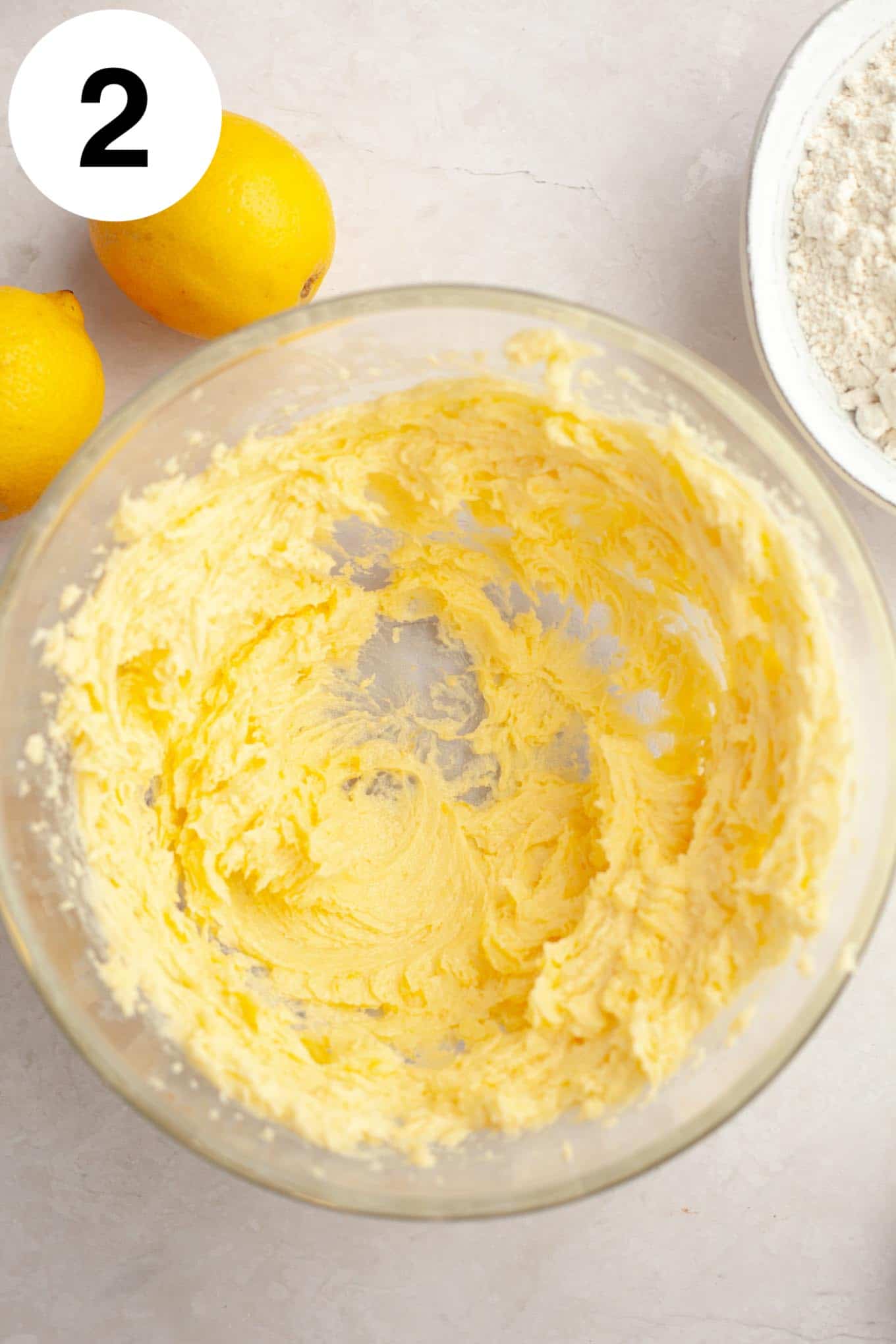 An overhead view of a creamed butter and sugar mixture in a glass mixing bowl. 