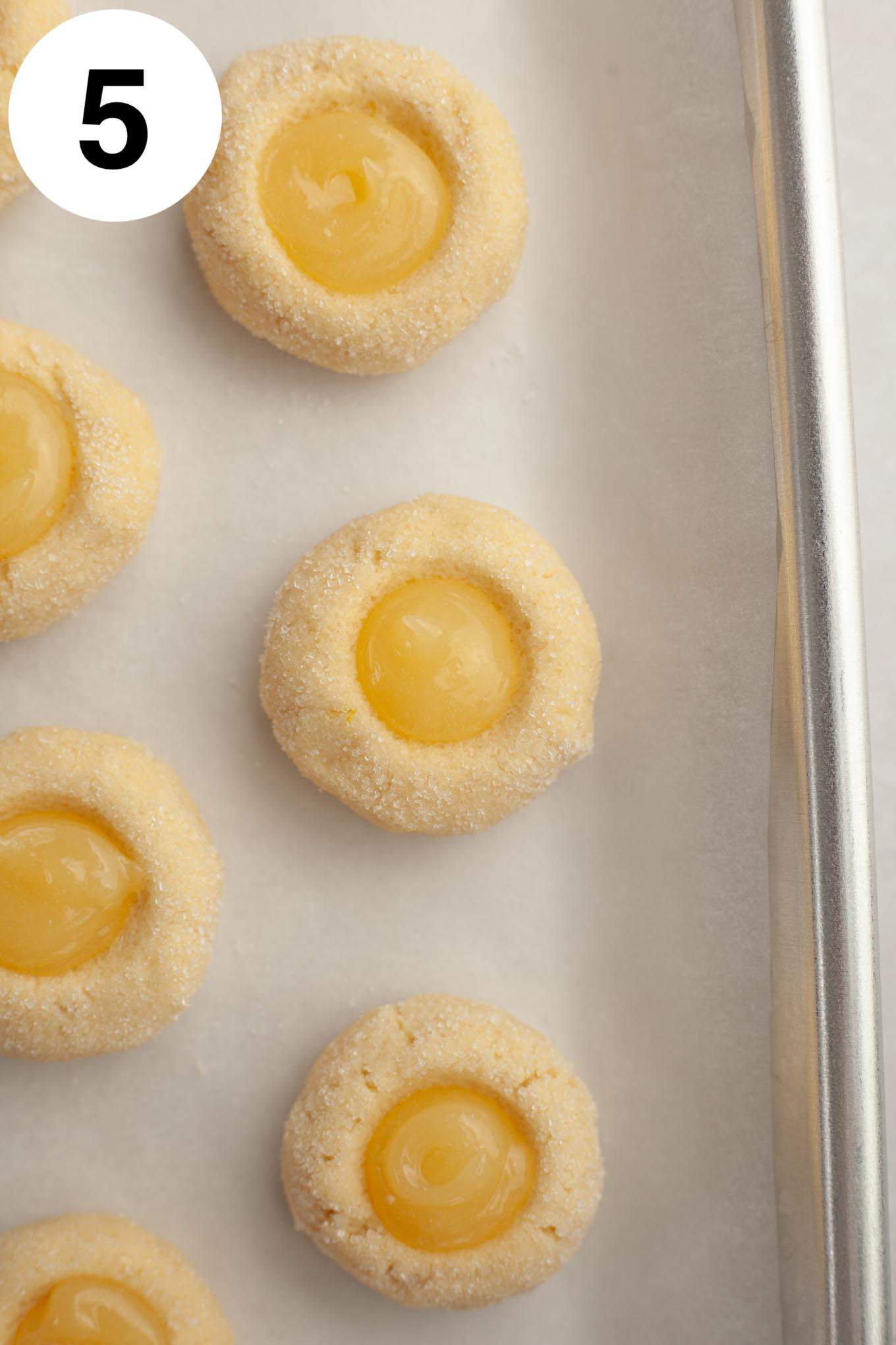 An overhead view of unbaked lemon cookies filled with lemon curd. 