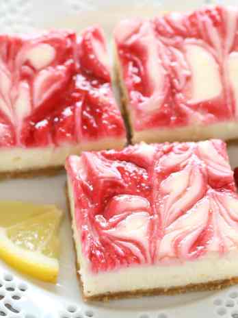 Three lemon raspberry cheesecake bars on a white dessert plate.