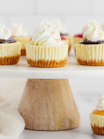 A marble cake stand with several mini cheesecakes with different toppings on them.