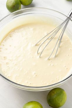 Key lime pie filling in a glass mixing bowl with a whisk.