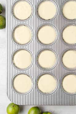 An overhead view of unbaked mini key lime pies in a muffin tin.