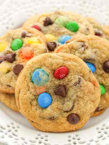 Several M&M's cookies on a decorative white plate.