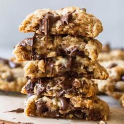 A stack of oatmeal chocolate chip cookies cut in half with melted chocolate running down the front.