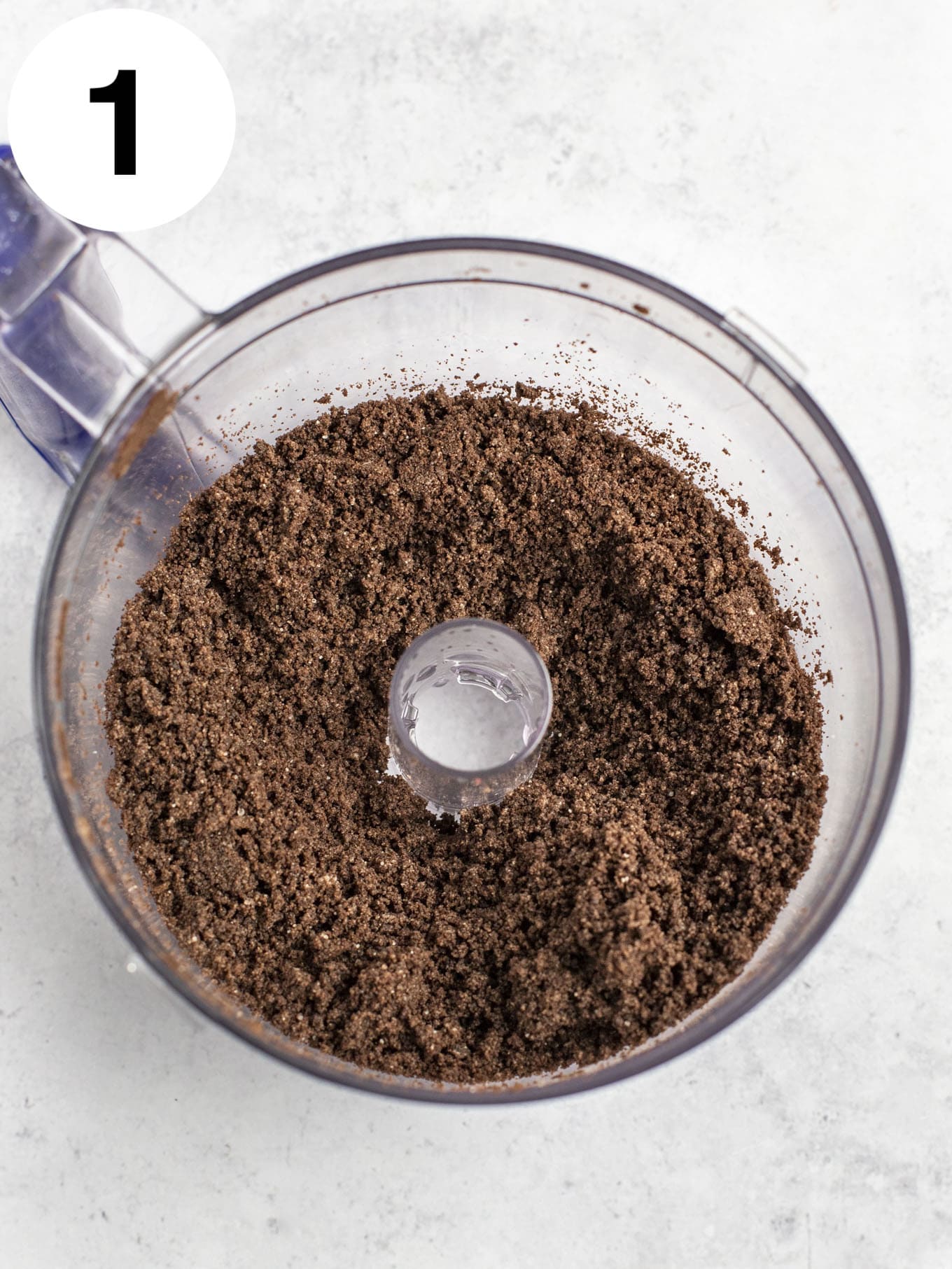An overhead view of Oreo crumbs in the bowl of a food processor. 