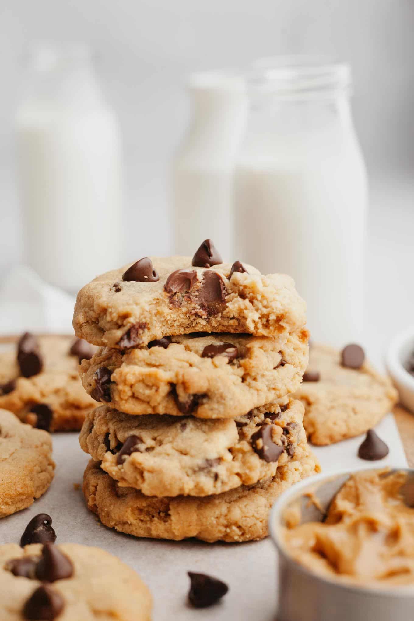 A stack of four peanut butter chocolate chip cookies; the top cookie has a bite missing.