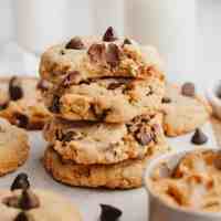 A stack of peanut butter chocolate chip cookies. The top cookie has a bite missing to show the texture.