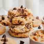 A stack of peanut butter chocolate chip cookies. The top cookie has a bite missing to show the texture.