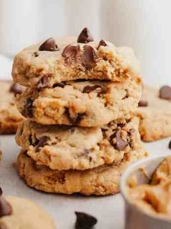 A stack of peanut butter chocolate chip cookies. The top cookie has a bite missing to show the texture.