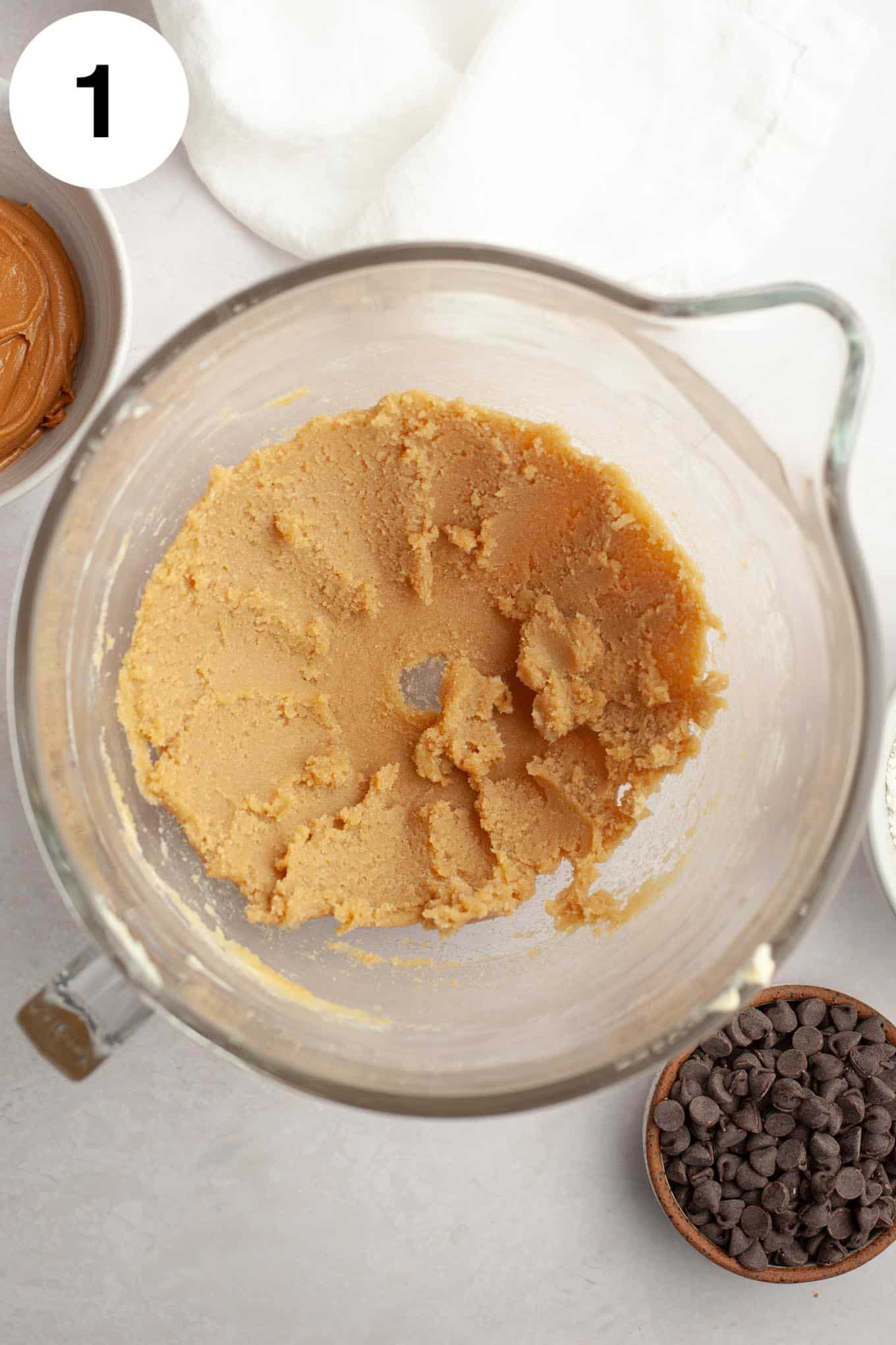 An overhead view of butter and sugar creamed together in a glass mixing bowl. 