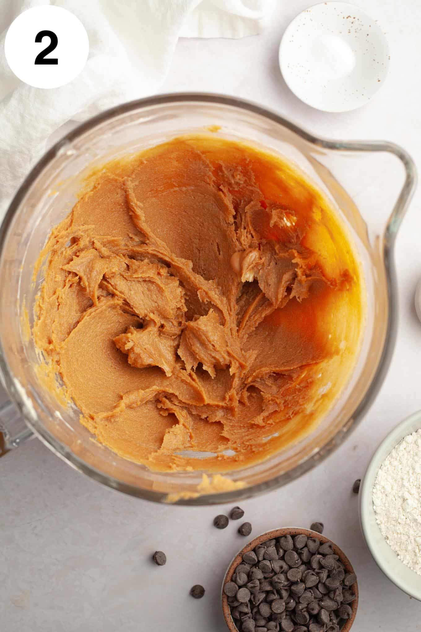 An overhead view of butter, sugar, and peanut butter creamed together in a glass mixing bowl. 