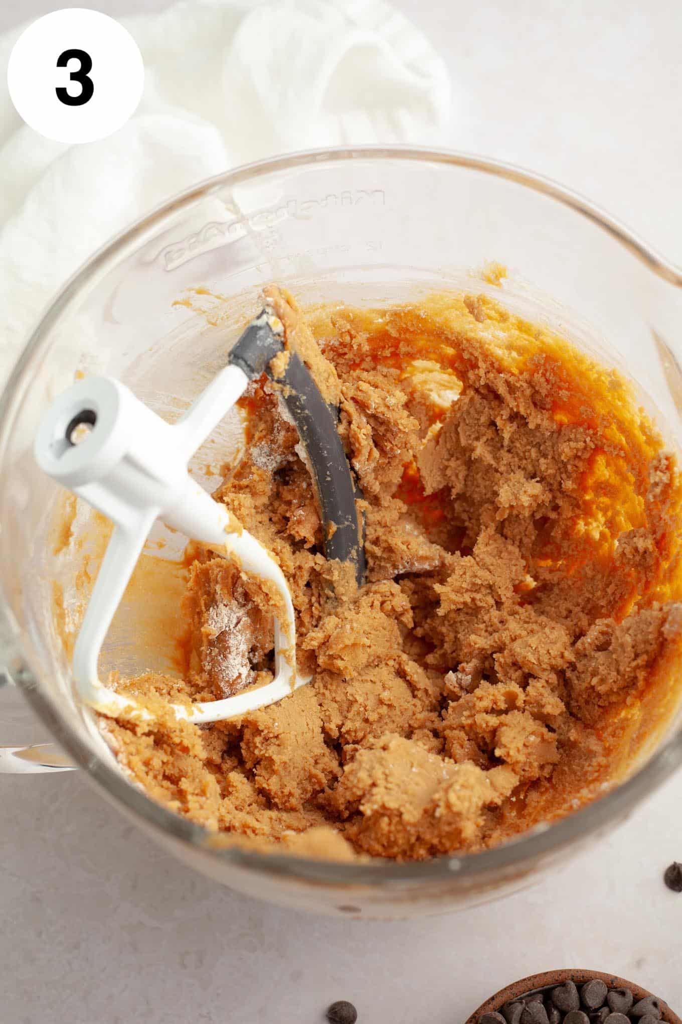 An overhead view of peanut butter cookie dough in a glass mixing bowl. 