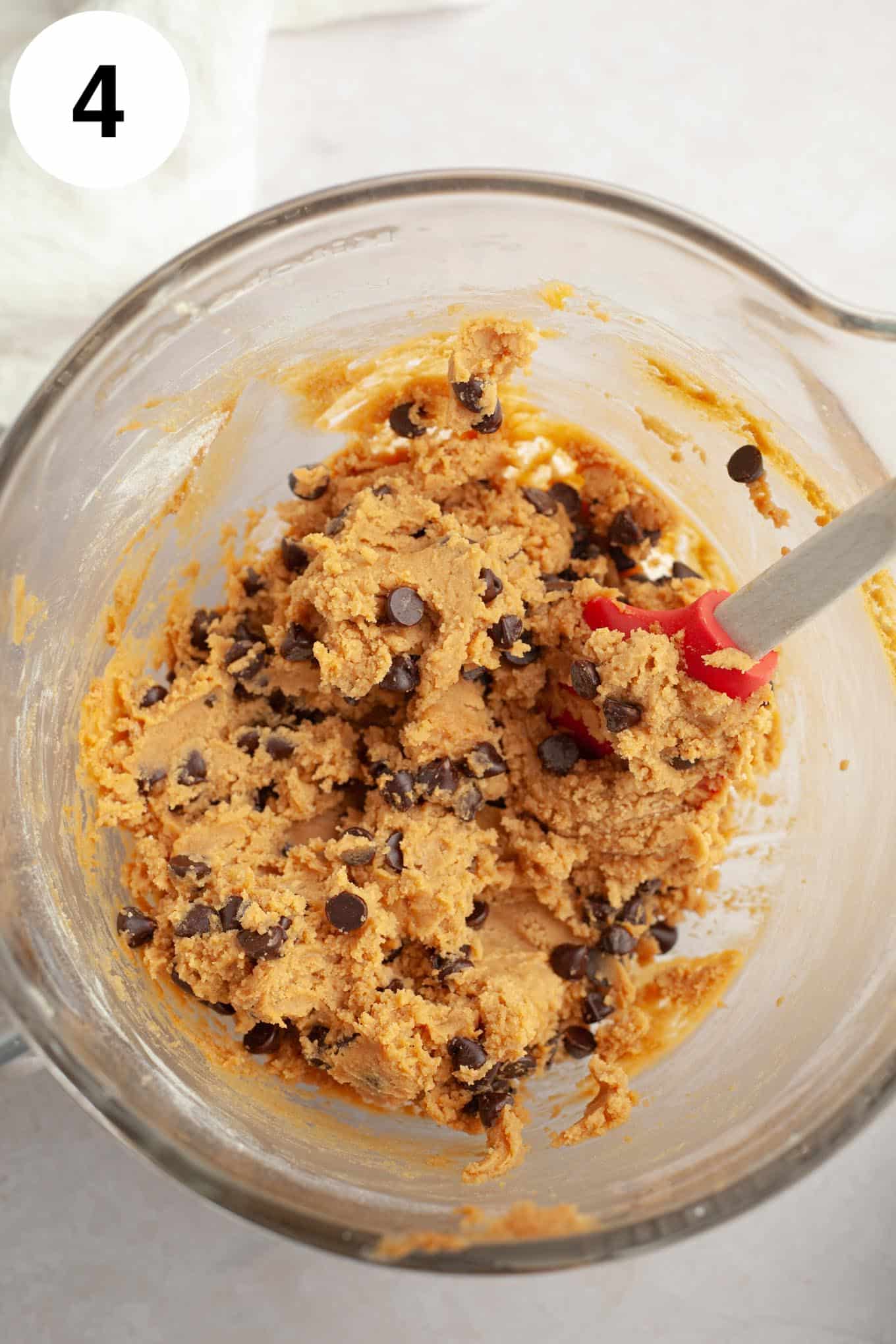 An overhead view of peanut butter chocolate chip cookie dough in a glass mixing bowl. 