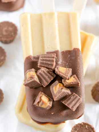 Peanut butter popsicles topped with magic shell and mini peanut butter cups. These Peanut Butter Cup Pudding Pops are a delicious and easy summer treat!