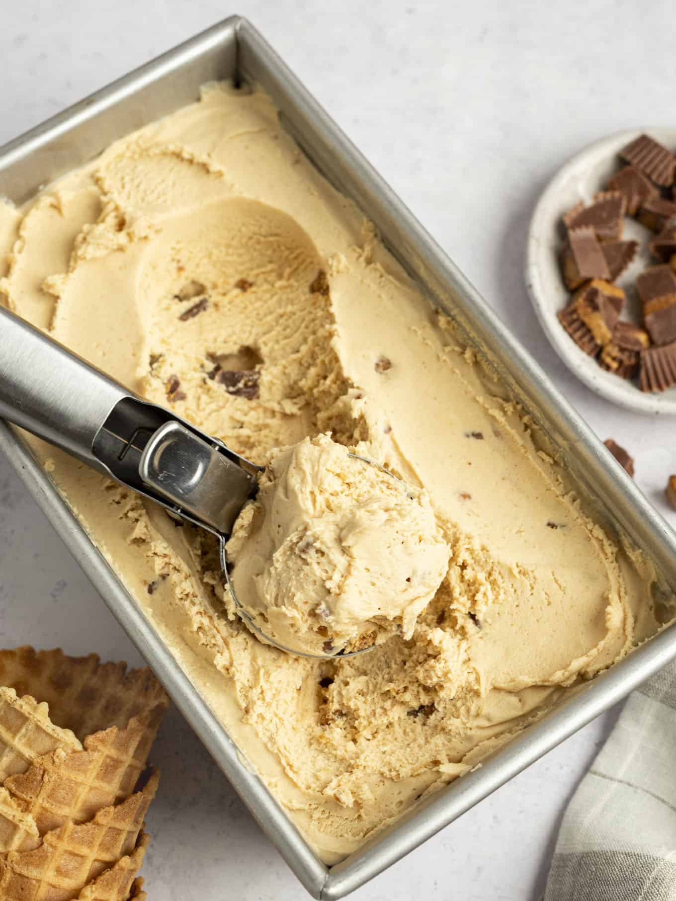 A loaf pan of peanut butter ice cream, with an ice cream scoop resting on top. 
