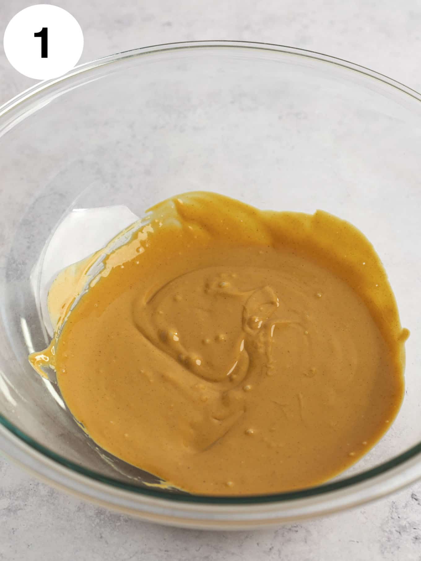 Melted peanut butter in a glass mixing bowl. 