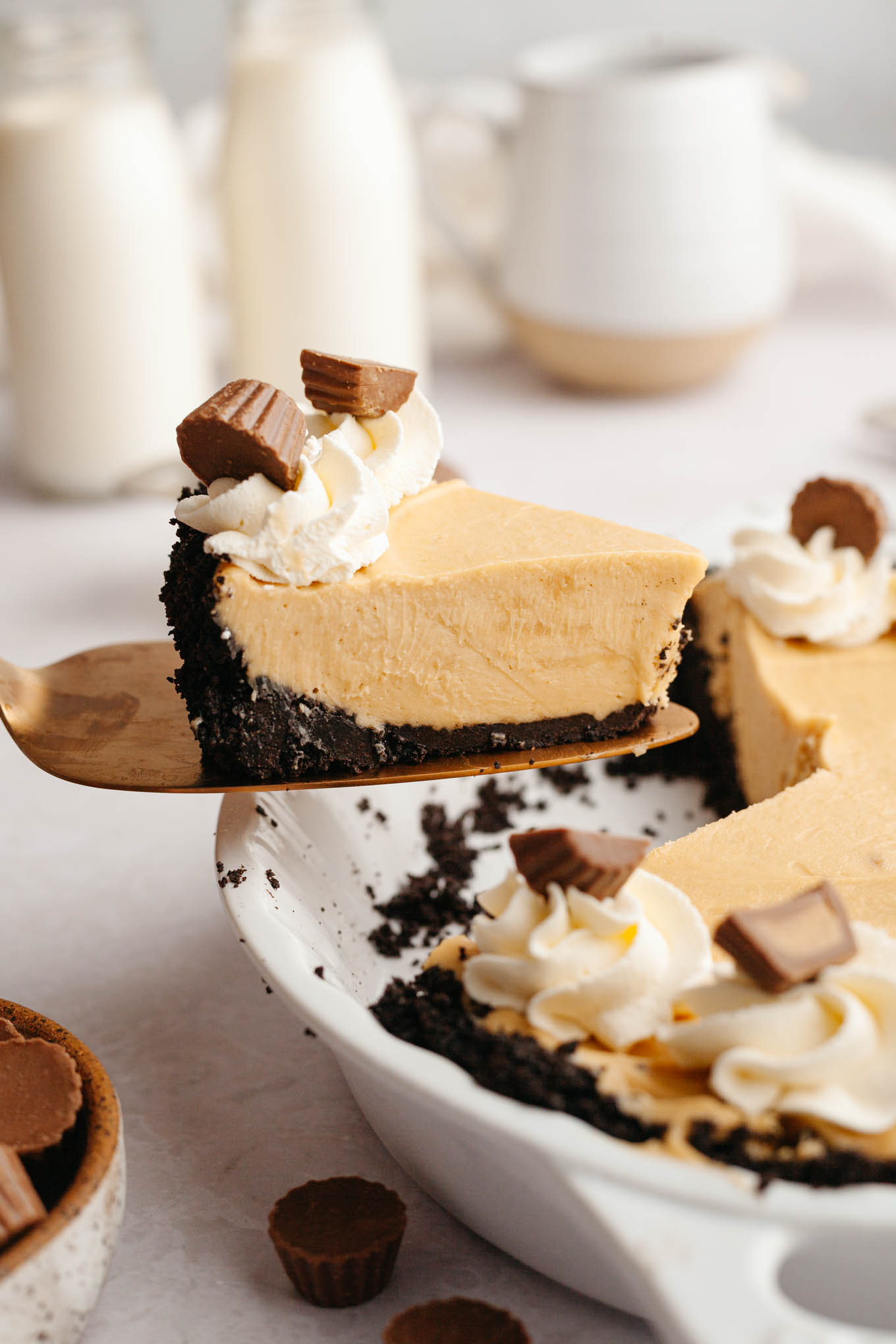 An action shot showing a slice of peanut butter pie being lifted from a pie plate. 