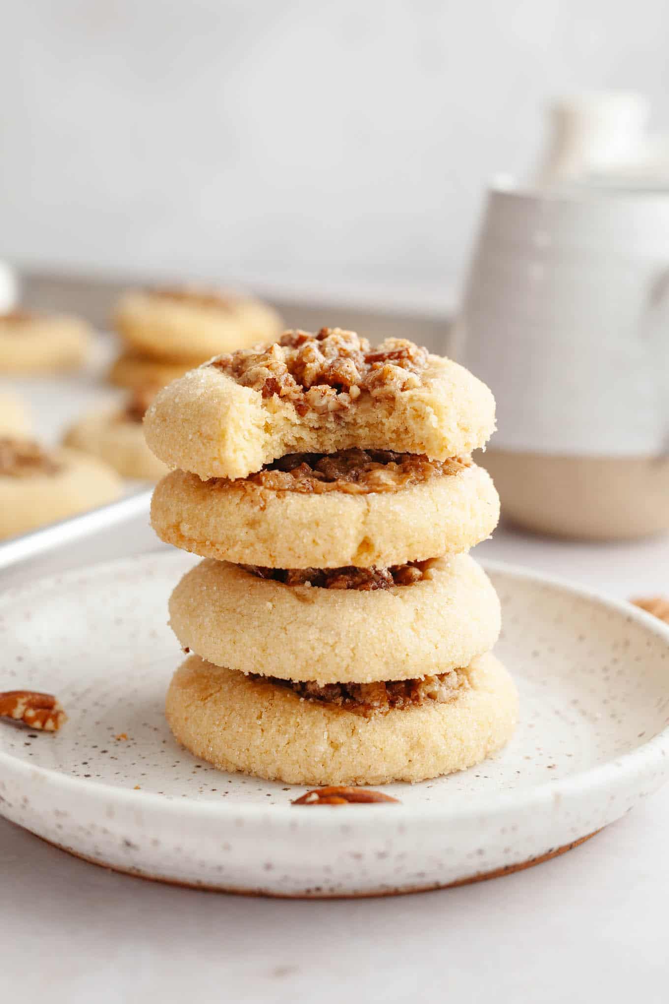 A stack of four pecan pie cookies, seen from the side. The top cookie has a bite missing.