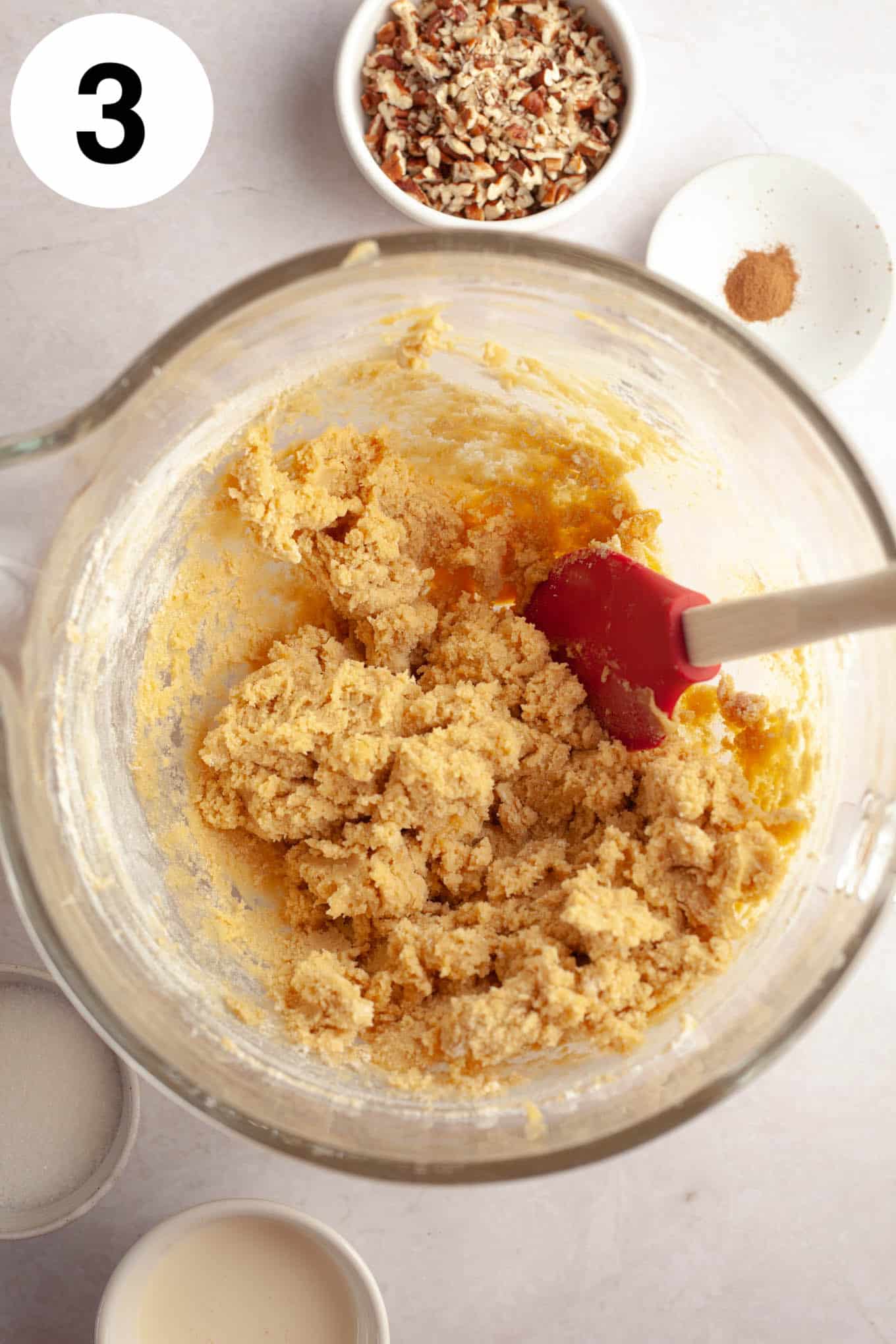 An overhead view of thumbprint cookie dough in a glass mixing bowl. 