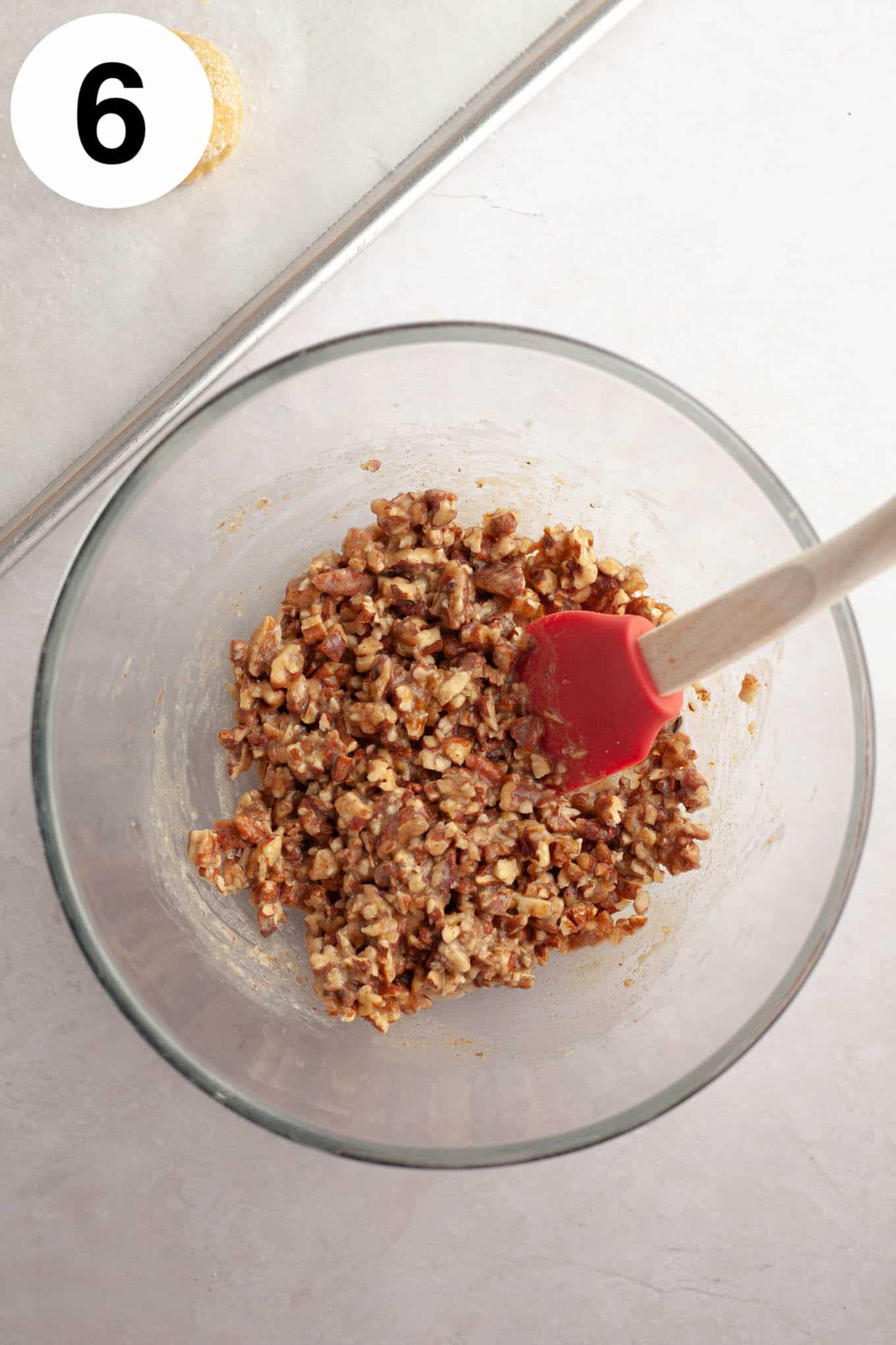 An overhead view of pecan pie filling for cookies in a glass mixing bowl. 