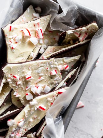 A metal loaf pan with pieces of peppermint bark topped with crushed candy canes.