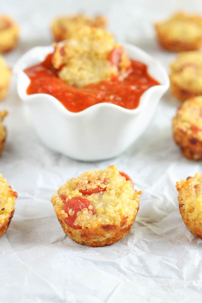 Several mini quinoa pizzas on a piece of parchment paper.