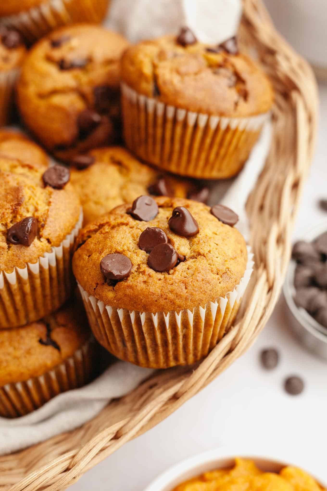 Chocolate chip and pumpkin muffins piled into a wicker serving basket. 