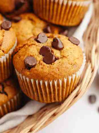 Several pumpkin chocolate chip muffins in a basket.