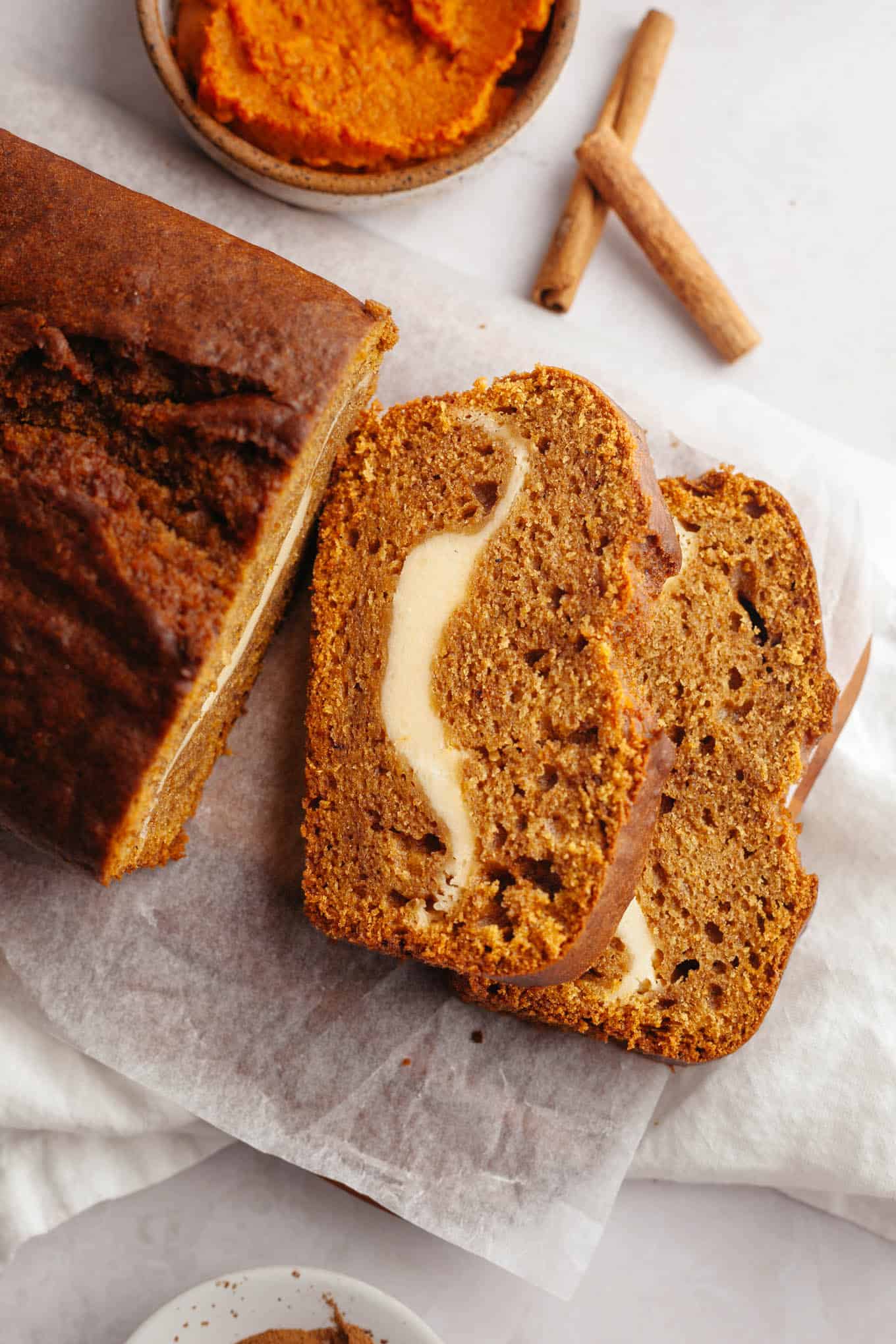 An overhead view of two slices of pumpkin cream cheese bread, on their sides. 
