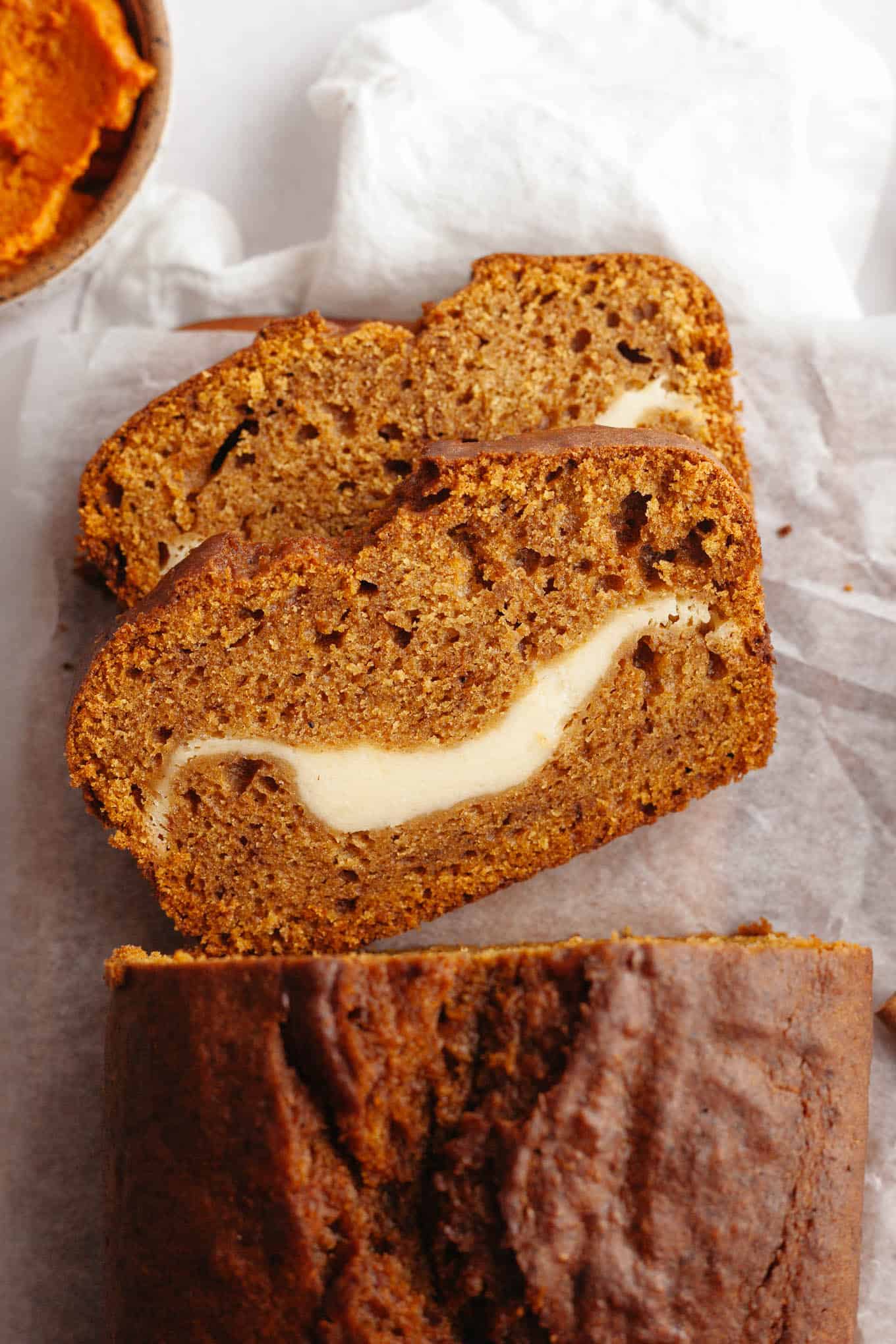 An overhead view of two slices of pumpkin cream cheese bread, on their sides. 