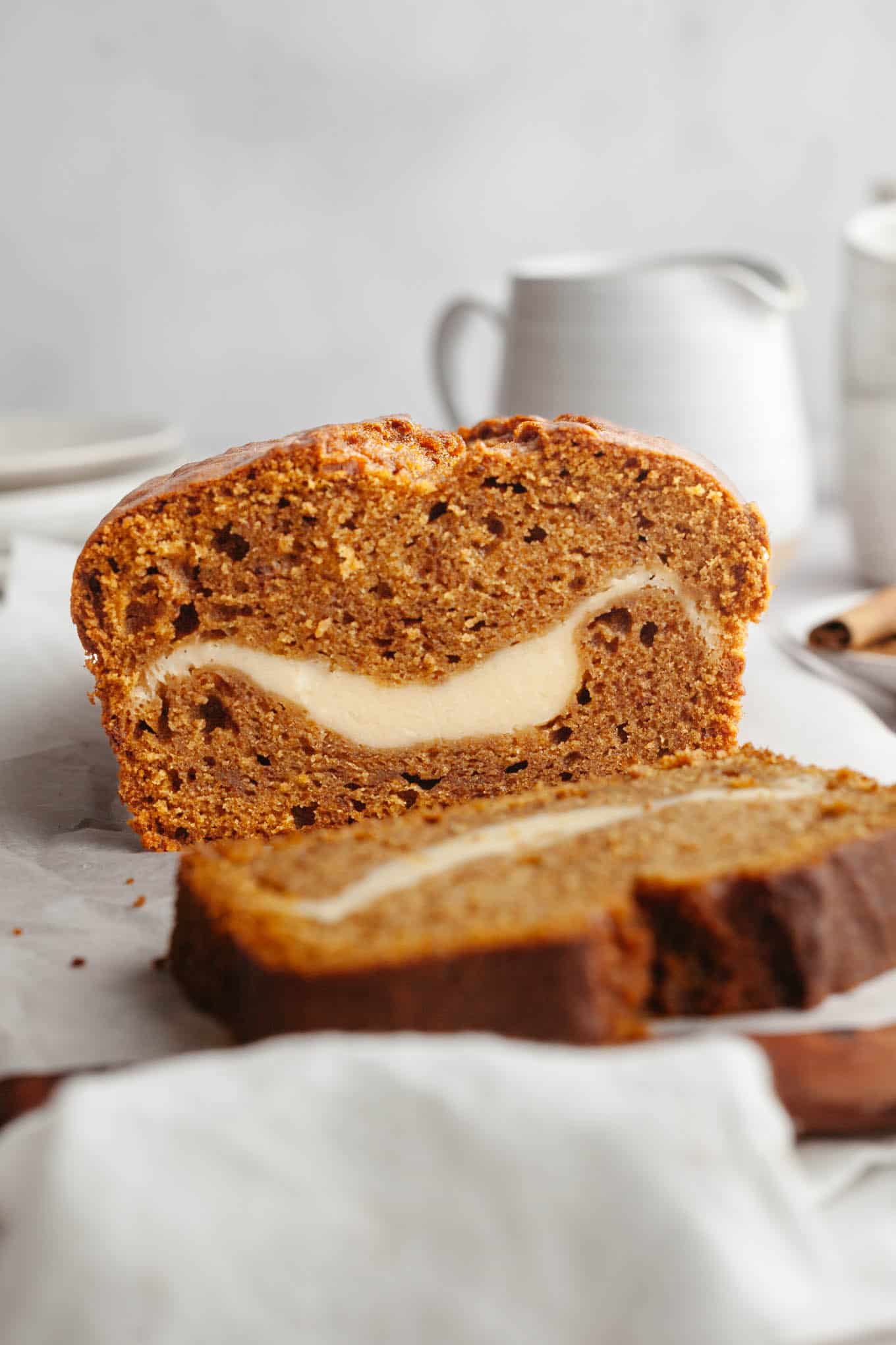 A side view of a loaf of pumpkin bread that's been sliced to reveal the cream cheese filling.
