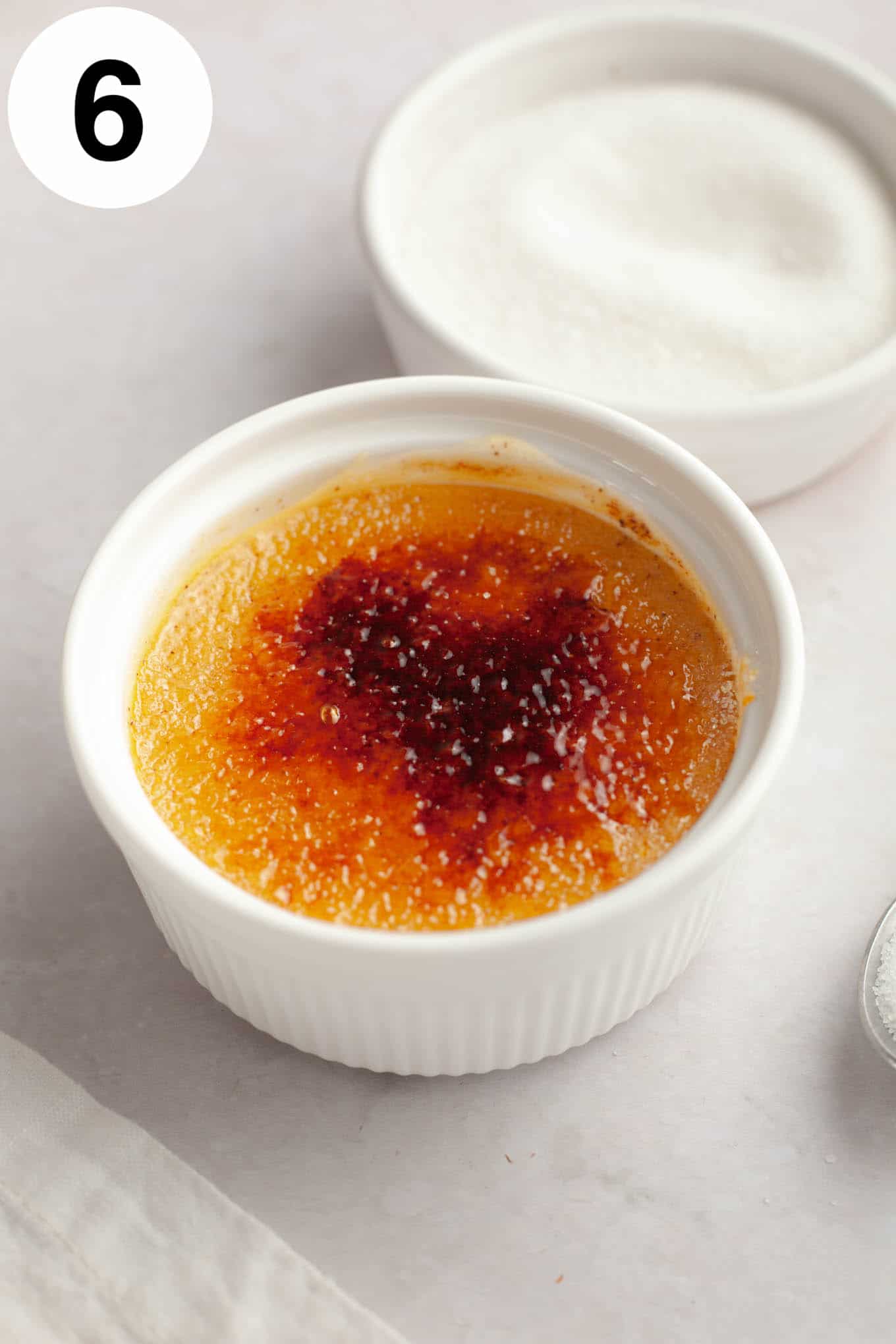 A ramekin of pumpkin spice crème brûlée, with a dish of sugar next to it. 