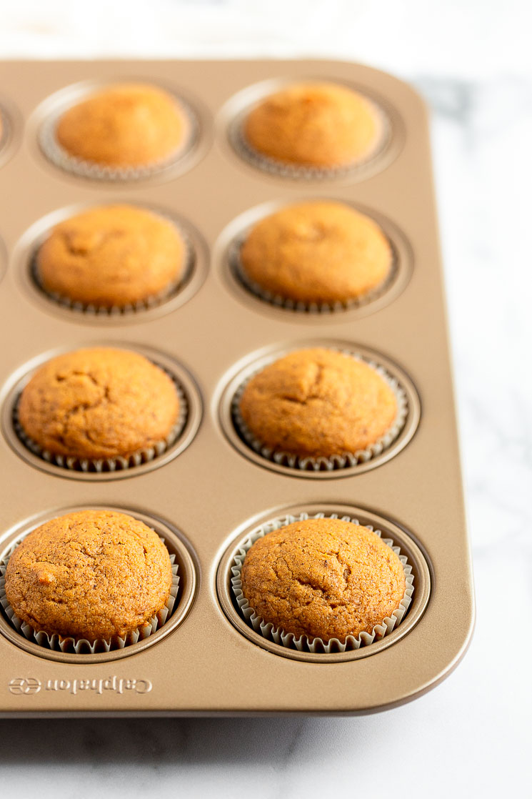 A muffin pan filled with pumpkin cupcakes fresh out of the oven.