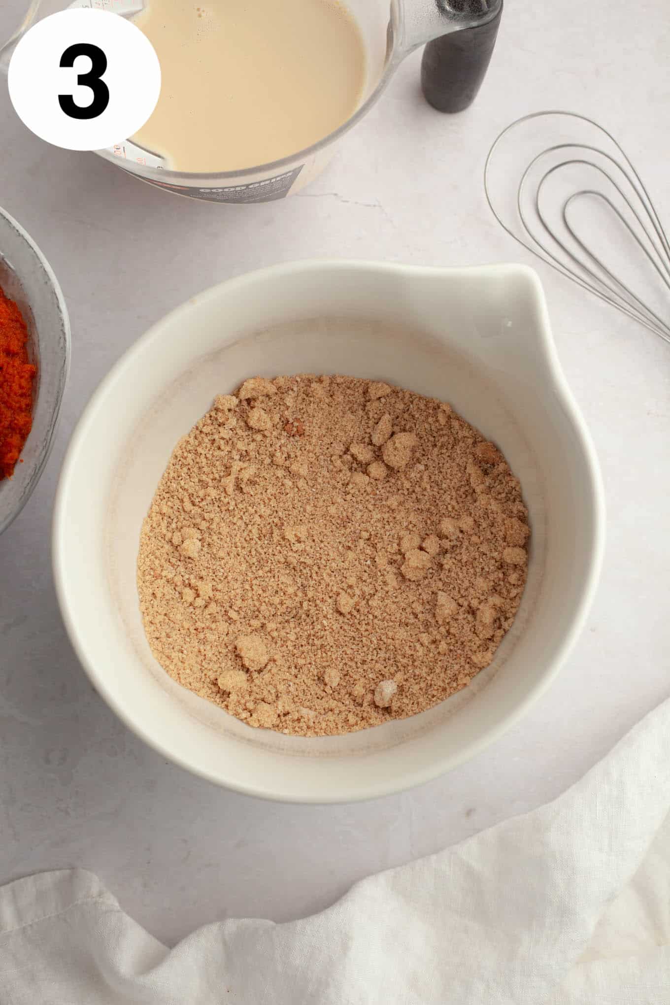 An overhead view of a flour and brown sugar mixture in a mixing bowl. 