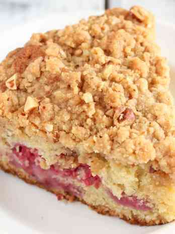 A slice of raspberry almond cake with crumb topping on a white plate.