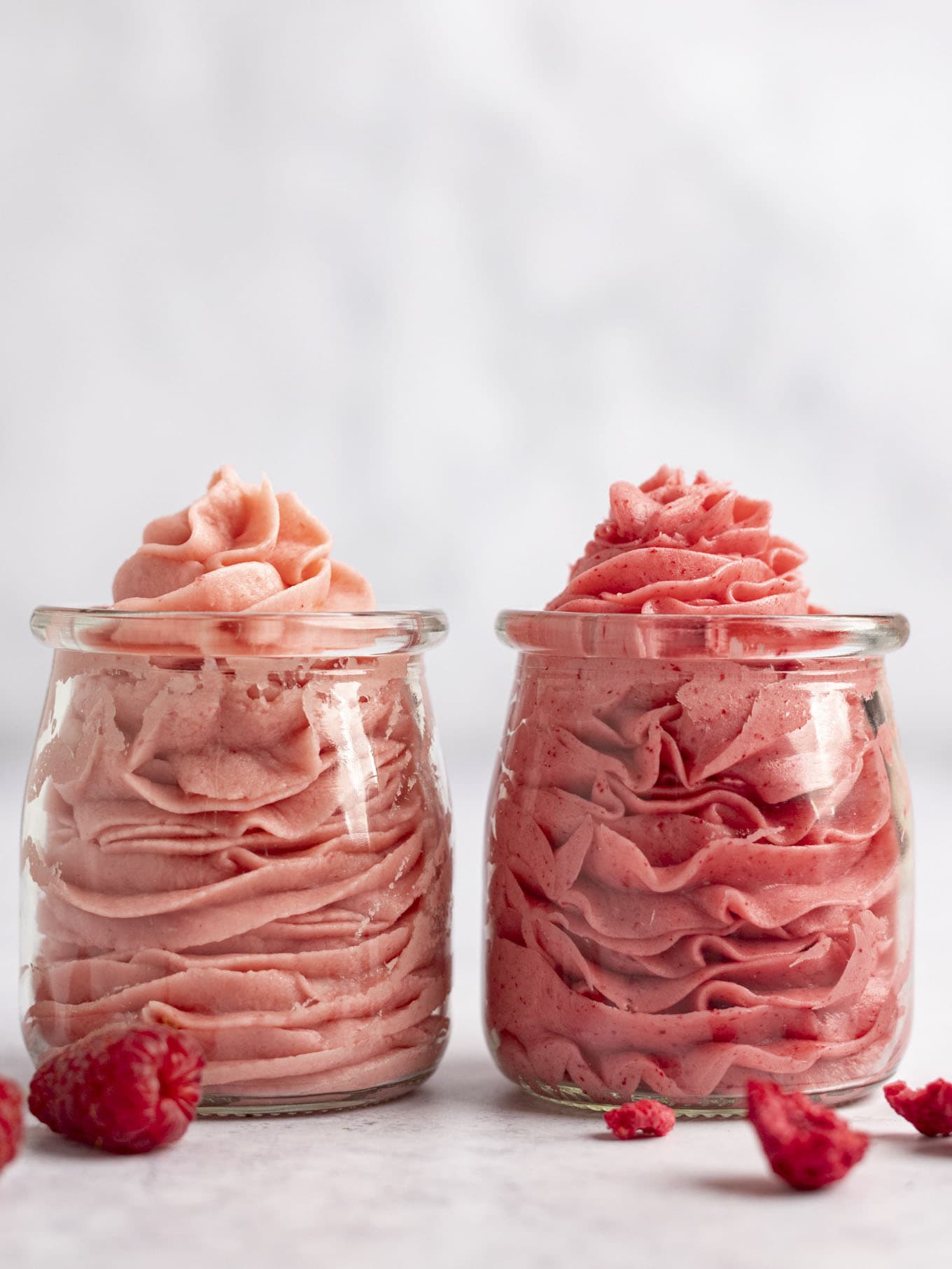 Two glass jars filled with raspberry frosting.