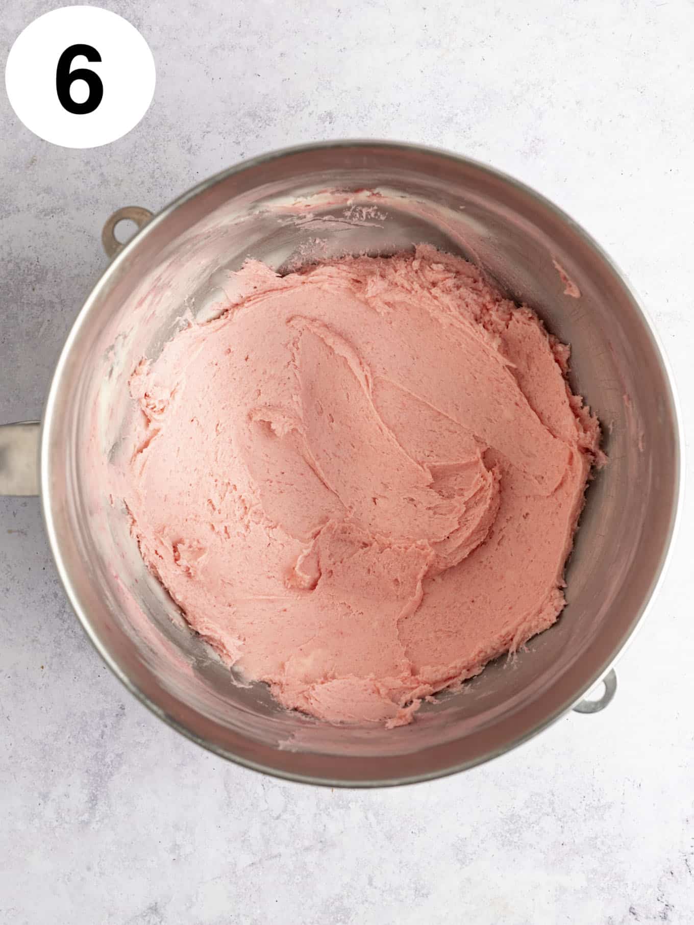 An overhead view of fresh raspberry frosting in a mixing bowl. 
