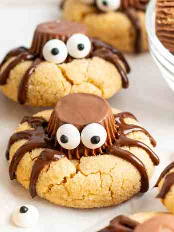 A closeup of spider cookies on a piece of parchment paper.
