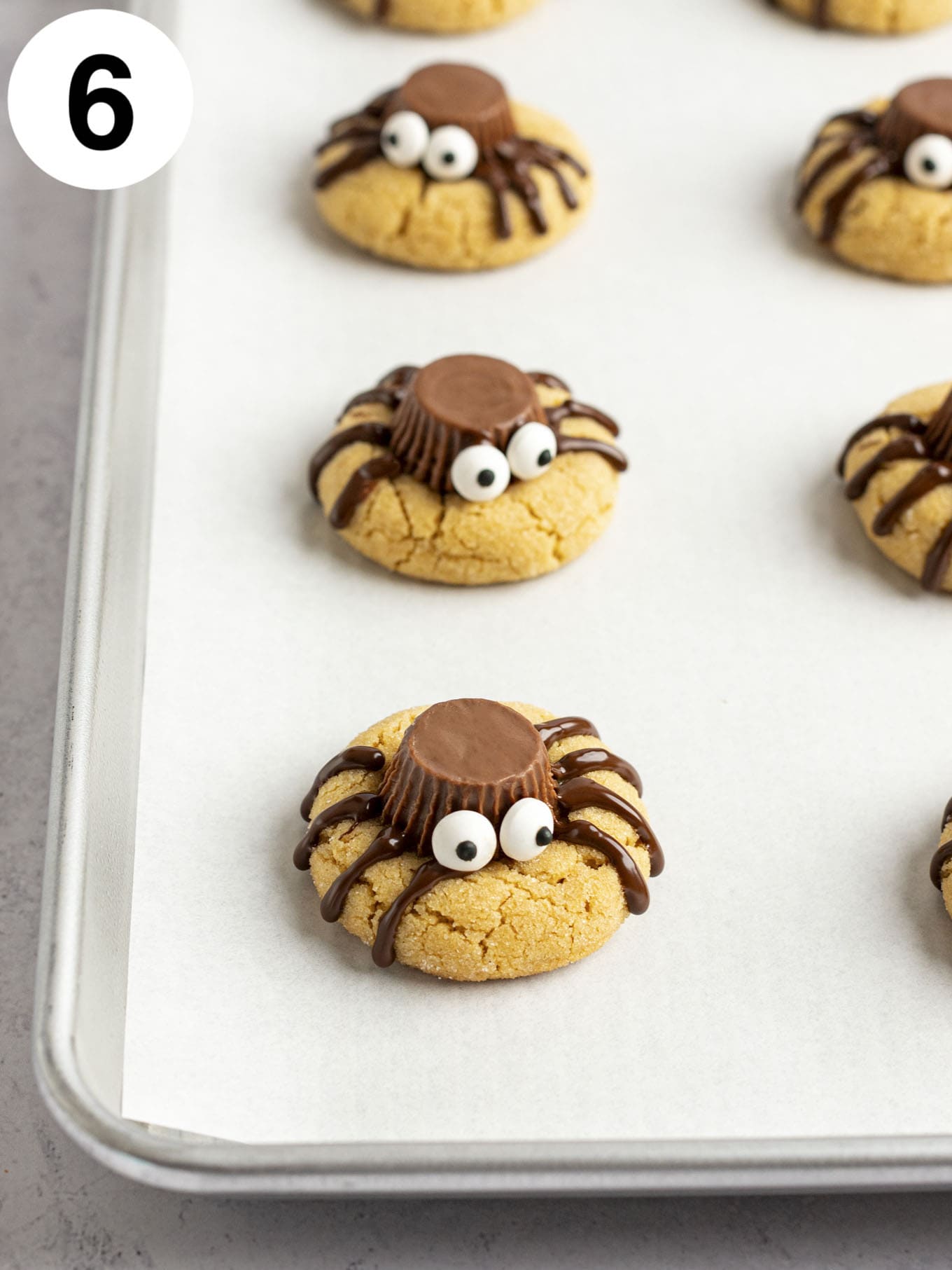 A process shot showing spider cookies after the candy eyes have been added. 