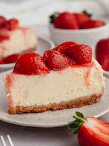 A slice of strawberry cheesecake on a white plate.