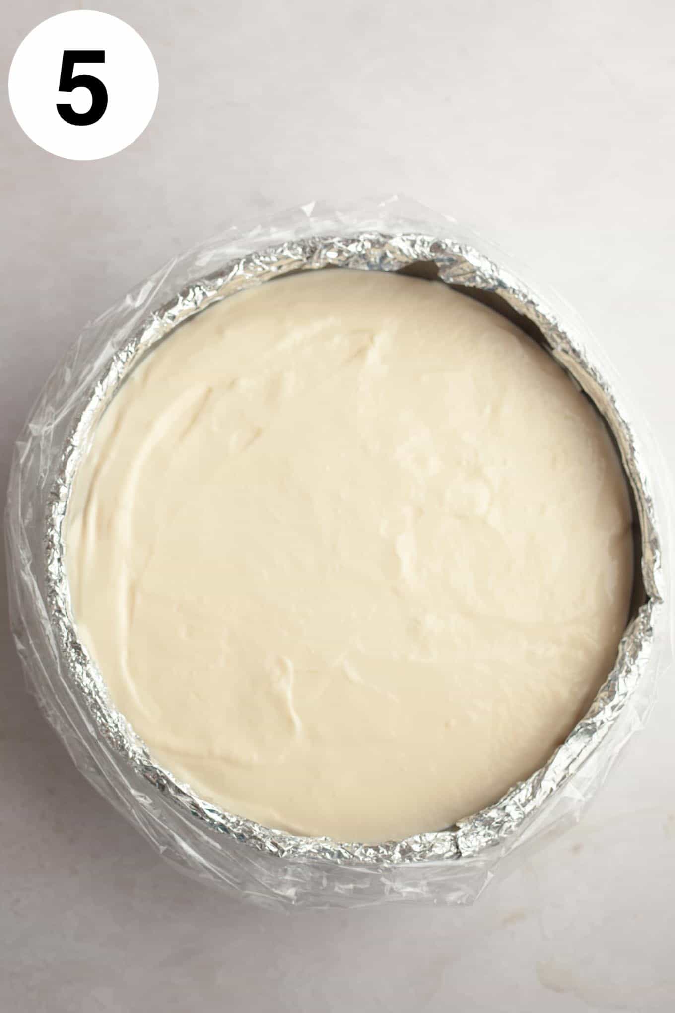 An overhead view of cheesecake filling in a springform pan that's been prepped for a water bath. 