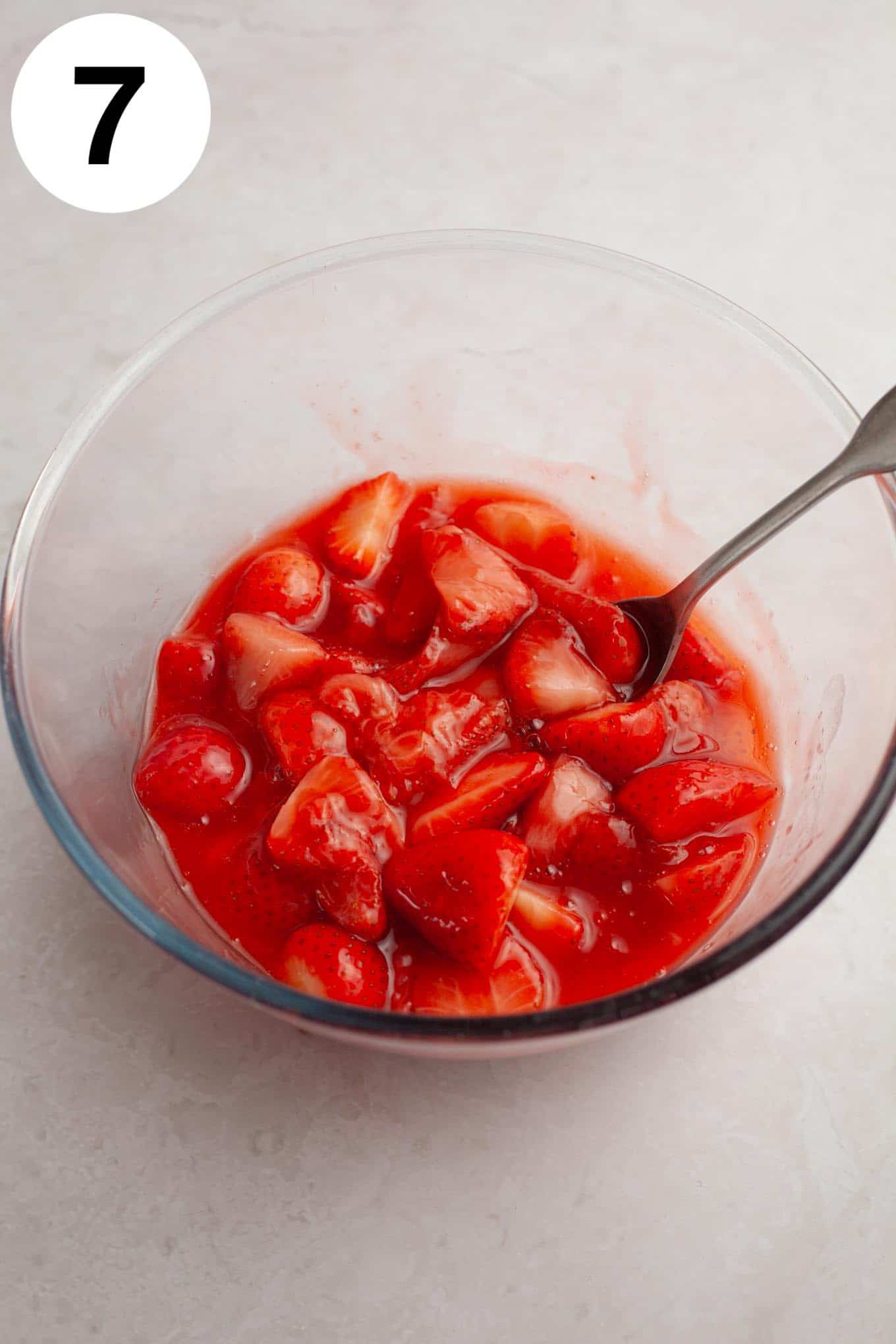 An overhead view of strawberry topping in a glass mixing bowl. 