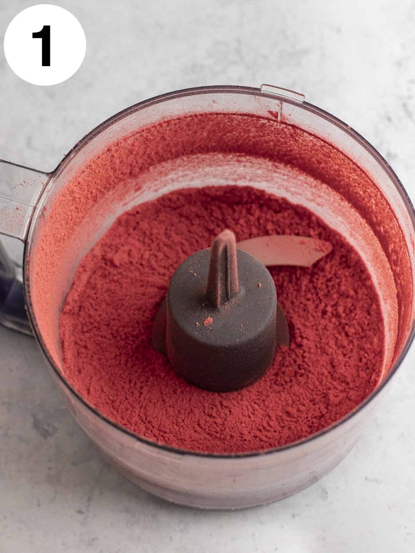 An overhead view of freeze-dried strawberry powder in the bowl of a food processor. 