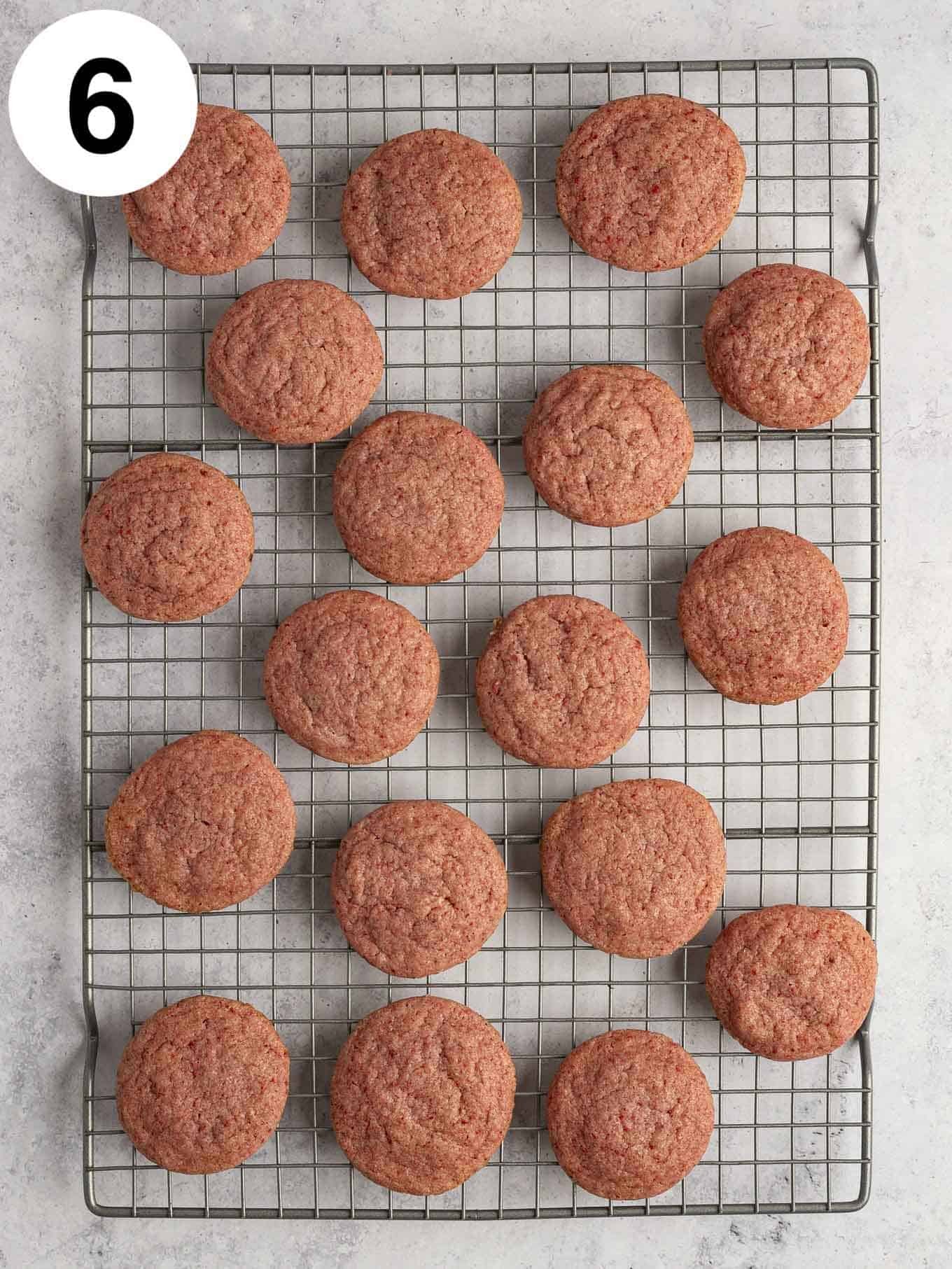 An overhead view of unfrosted strawberry cookies on a wire cooling rack. 