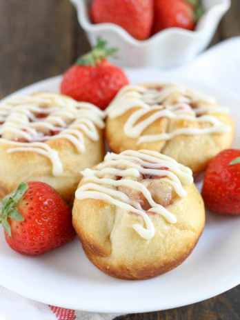 Three strawberry cinnamon rolls on a white plate.