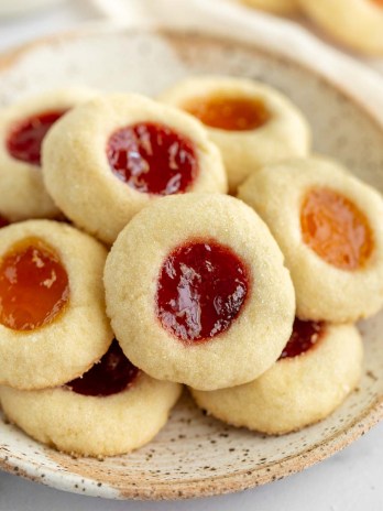 Thumbprint cookies sitting on top of a speckled plate.