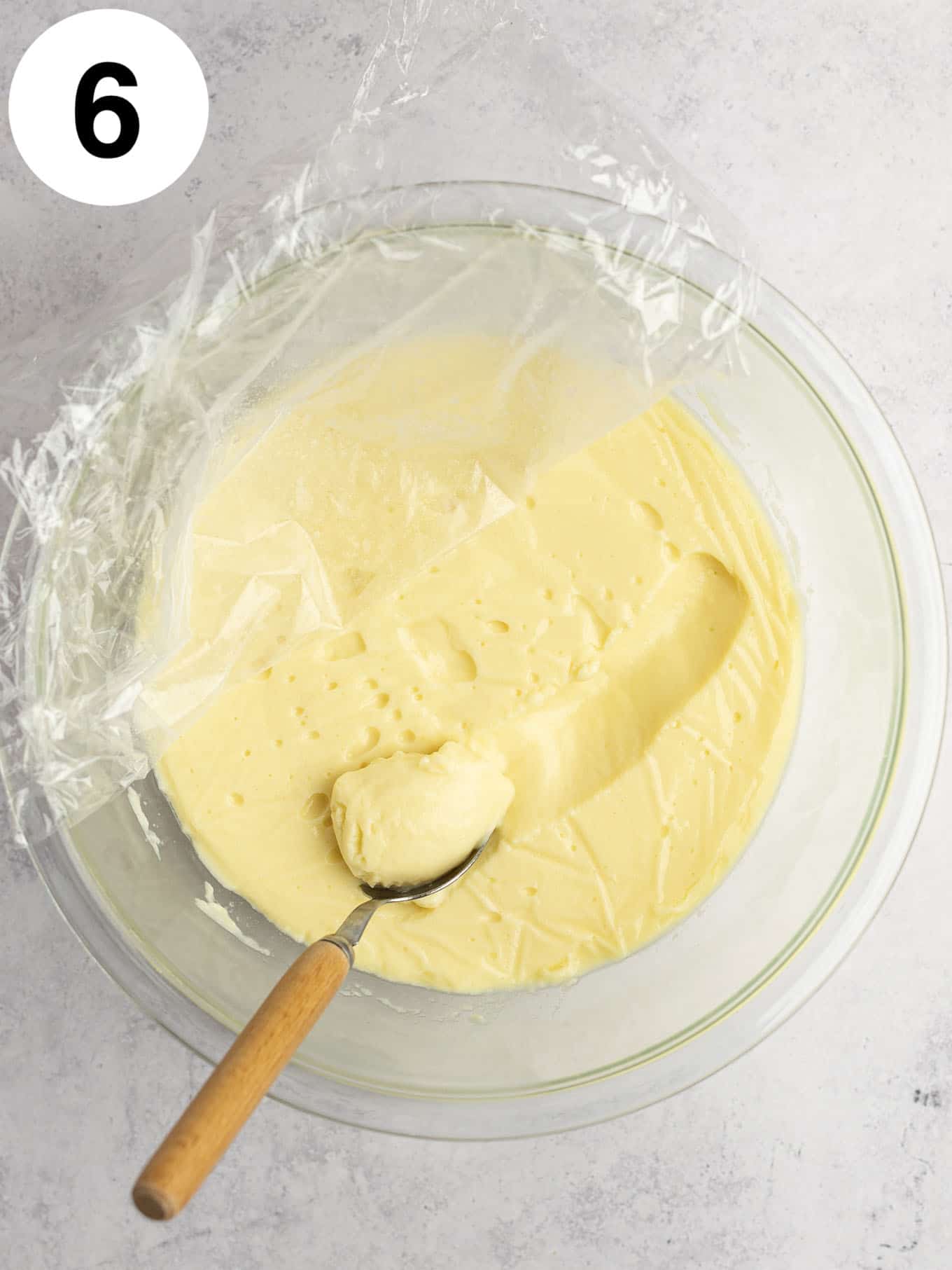 A glass bowl with the plastic wrap peeled back to reveal the pudding. 